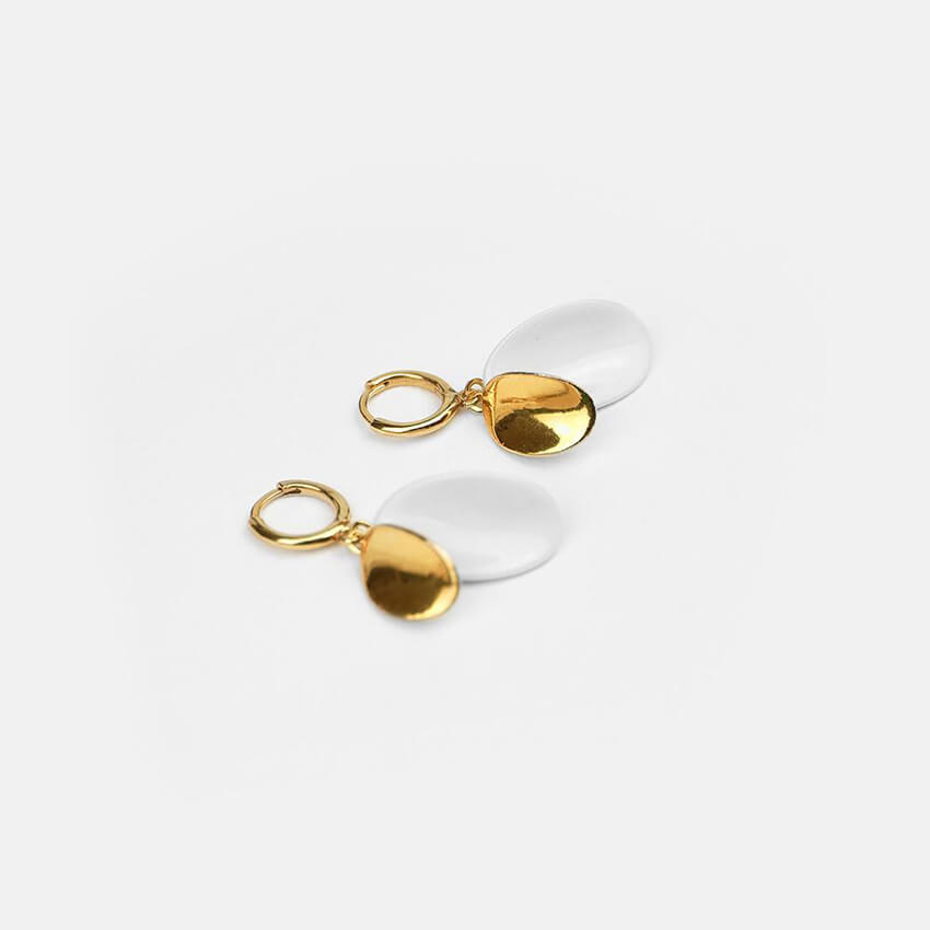 Exquisite white and gold earrings on a light grey background. Exclusive and minimal design.