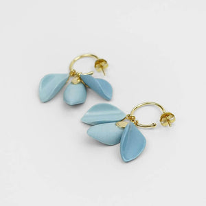 Light grey background for two beautiful blue ceramic earrings. They seem like a delicate blue flower.