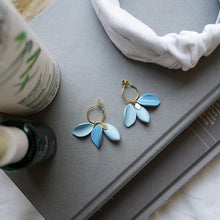 Load image into Gallery viewer, Lifestyle photograph: light blue porcelain earrings, white headpiece, books, and Kiehl&#39;s skincare  products.