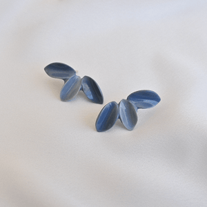 Three petals earrings. Refined jewellery on a grey background. 