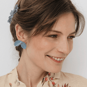 A Brunette model smiling gracefully is wearing stunning soft blue porcelain earrings.