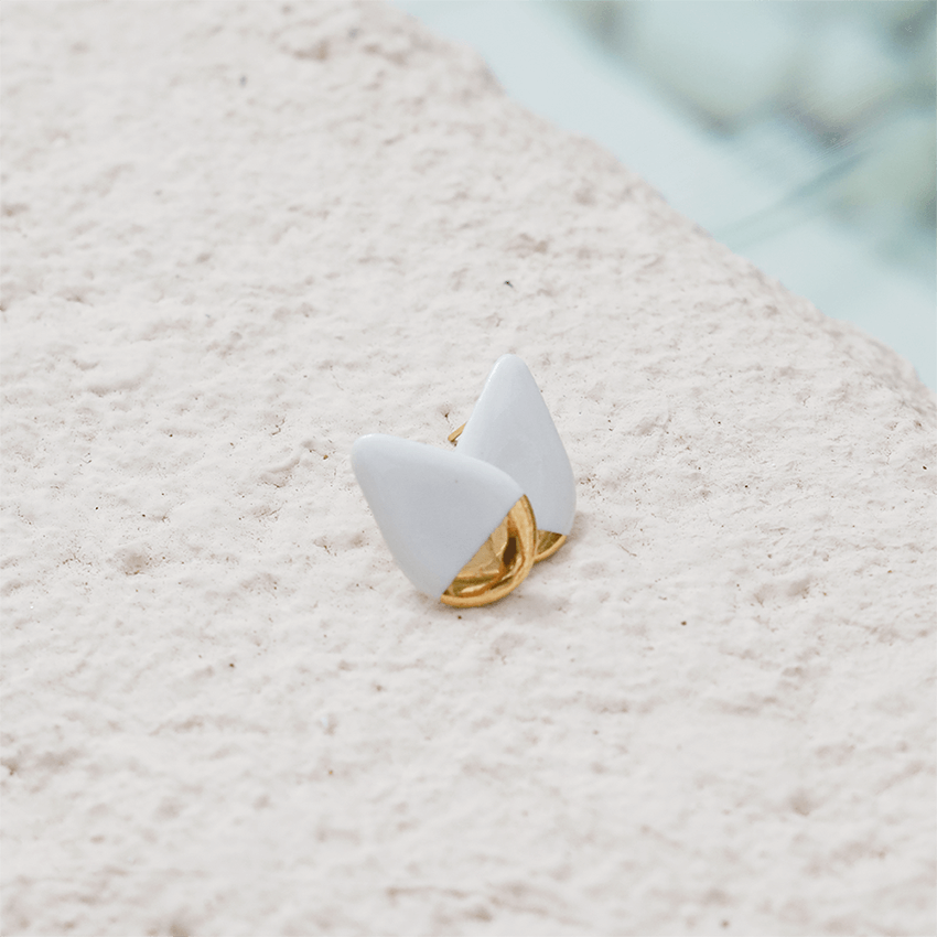 White and gold porcelain earrings. Bright photography.