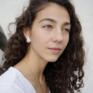 Young woman wearing a delicate white and gold porcelain earring.