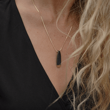 Load image into Gallery viewer, Minimal jewellery design: black and gold porcelain pendant on a gold chain. 