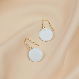 Dangle earrings with minimal style. Delicate porcelain jewels with gold accents on a soft pink background. 