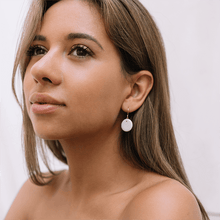 Load image into Gallery viewer, Portrait of a young woman wearing round white porcelain earrings. 