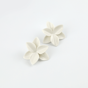 A collection of white porcelain floral earrings designed specifically for brides, adding an elegant and delicate touch to their hairstyle.