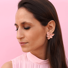 Load image into Gallery viewer, Soft pink delicate earrings made of porcelain, highlighting its elegance and intricate design, adding a touch of grace to the woman&#39;s outfit. Soft pink backdrop matching the floral earrings.