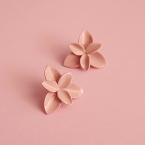 Detailed scene of elegant soft pink flower earrings. Soft pink background. Colorful image. 