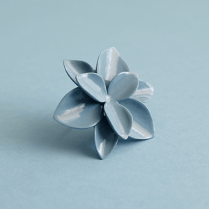 A blue porcelain ring, featuring a unique and captivating design, adding a pop of color to any outfit. Matching blue background. 
