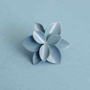 Fine ring close-up: contemporary porcelain jewelry. Stunning blue flower ring on a blue background. 
