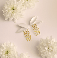 Load image into Gallery viewer, Contemporary porcelain jewellery: elegant bridal hair pins. Asymmetric white porcelain hairpins – two delicate leaves, each. Beautiful detail to minimal brides. Product close-up surrounded by natural white flowers.