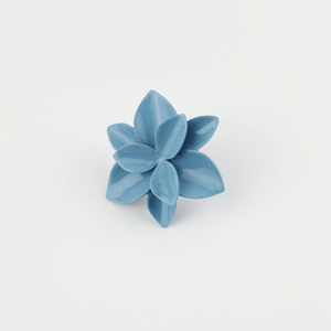 Contemporary ceramics artisanal work. Nature-inspired jewelry. Impressive artisanal work. Blue flower ring on a bright background. 