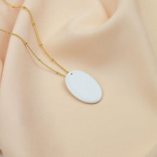 Load image into Gallery viewer, Exquisite white porcelain pendant on an elegant gold plated chain. Luminous product photography.