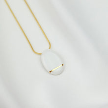 Load image into Gallery viewer, Gold necklace with a light white pendant made of porcelain. 