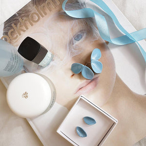 Lifestyle photography: book, two soft blue porcelain earrings, nail polish and skin care products.