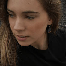 Load image into Gallery viewer, Black clay earrings. Young woman wearing minimal contemporary jewels with a black t-shirt. 