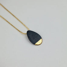 Load image into Gallery viewer, Close-up of a matte black porcelain pendant with gold detail. Light grey background. 