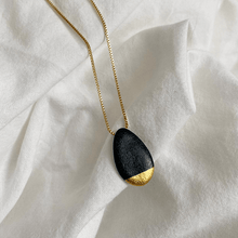 Load image into Gallery viewer, Close up: a contemporary black porcelain necklace on a linen white background.