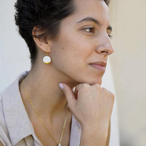 Round clay earrings with a gold detail. Young woman wearing a minimal jewelry set. 