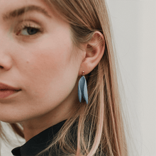 Load image into Gallery viewer, Woman looking straight into the camera. She&#39;s blond and is wearing timeless earrings made of light blue porcelain.