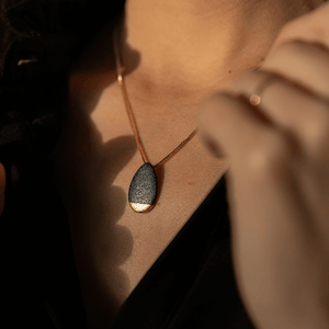 Sunny light product close-up: ceramic necklace with minimal design. 