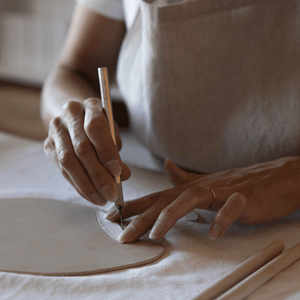 Studio scene: the artisan is cutting the raw porcelain with a bistoury.