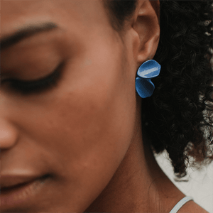 Close-up scene: strong blue ceramic earrings. Modern floral design. 