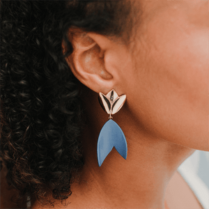 Woman wearing strong blue ceramic earrings. Minimalist clay artwork. 