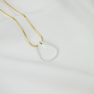 White porcelain pendant. Gold plated chain. Clean background. 
