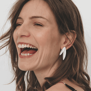 The model is smiling gracefully. Two leaves earrings. Elegant and timeless jewels.