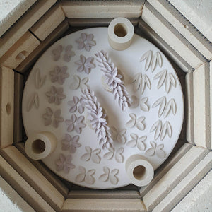 Porcelain artwork. Singular composition of raw porcelain pieces on kiln layer. The raw pieces are ready to be fired. 